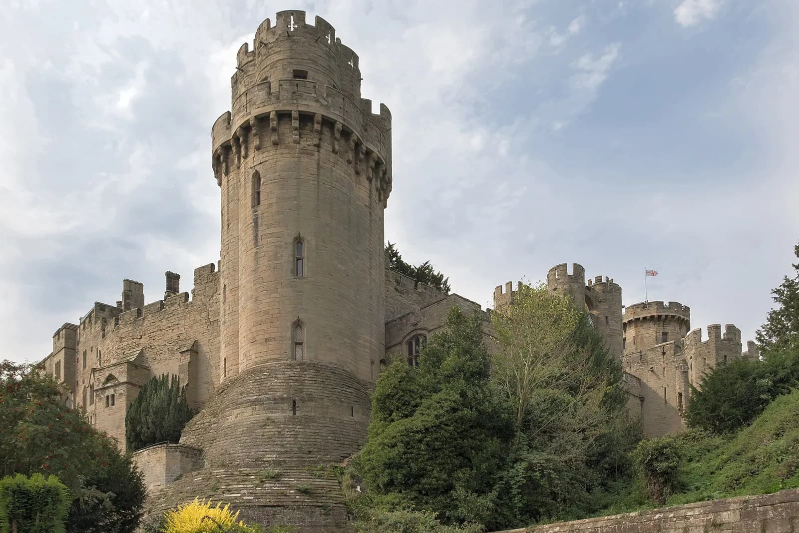 Caesar's Tower at Warwick Castle rising above trees and the castle walls