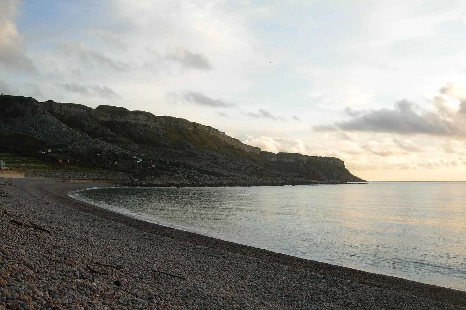 The long curve of shingle at Chesil Beach below the cliffs of Portland, at dusk