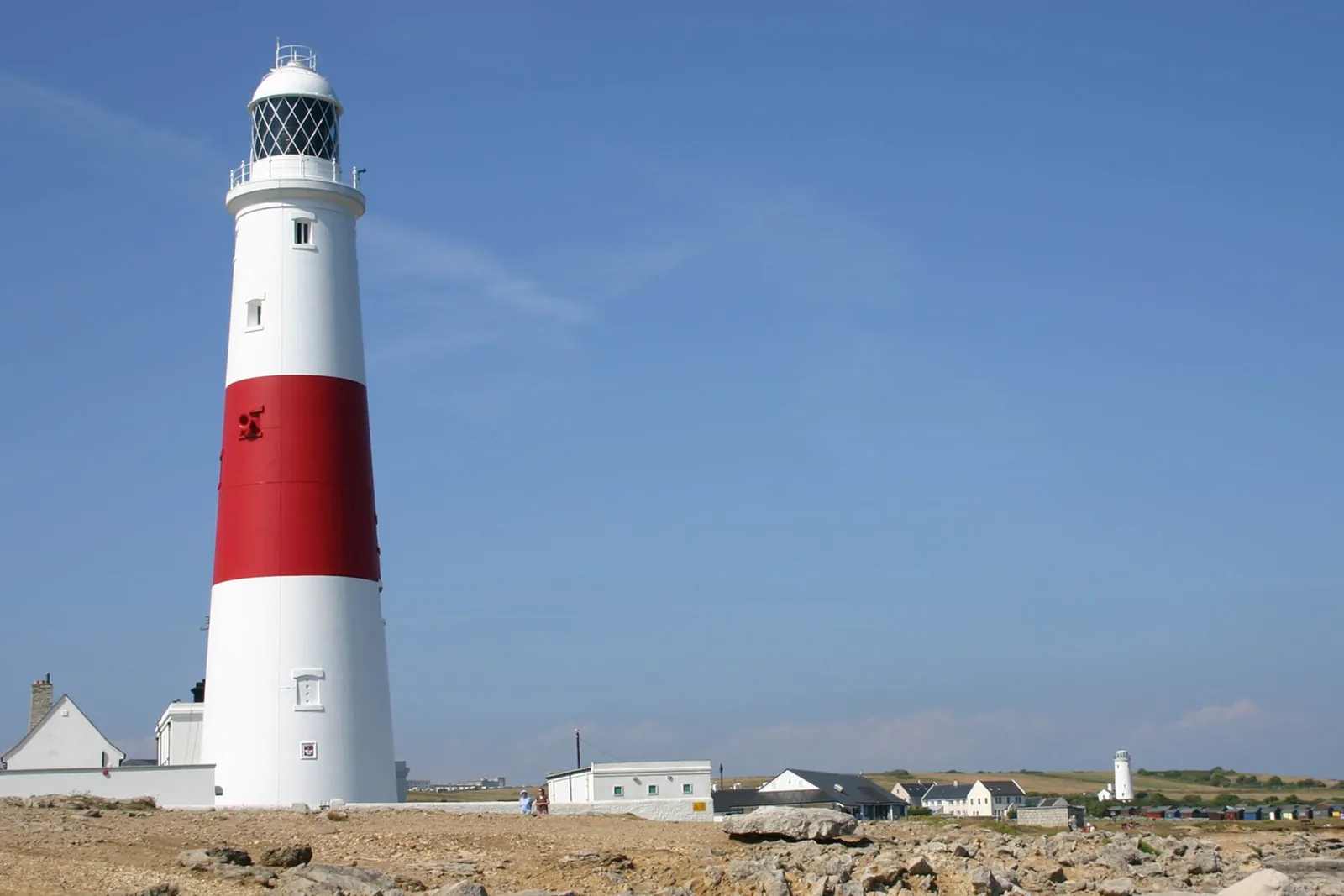 The red and white lighthouse at Portland Bill under a blue sky