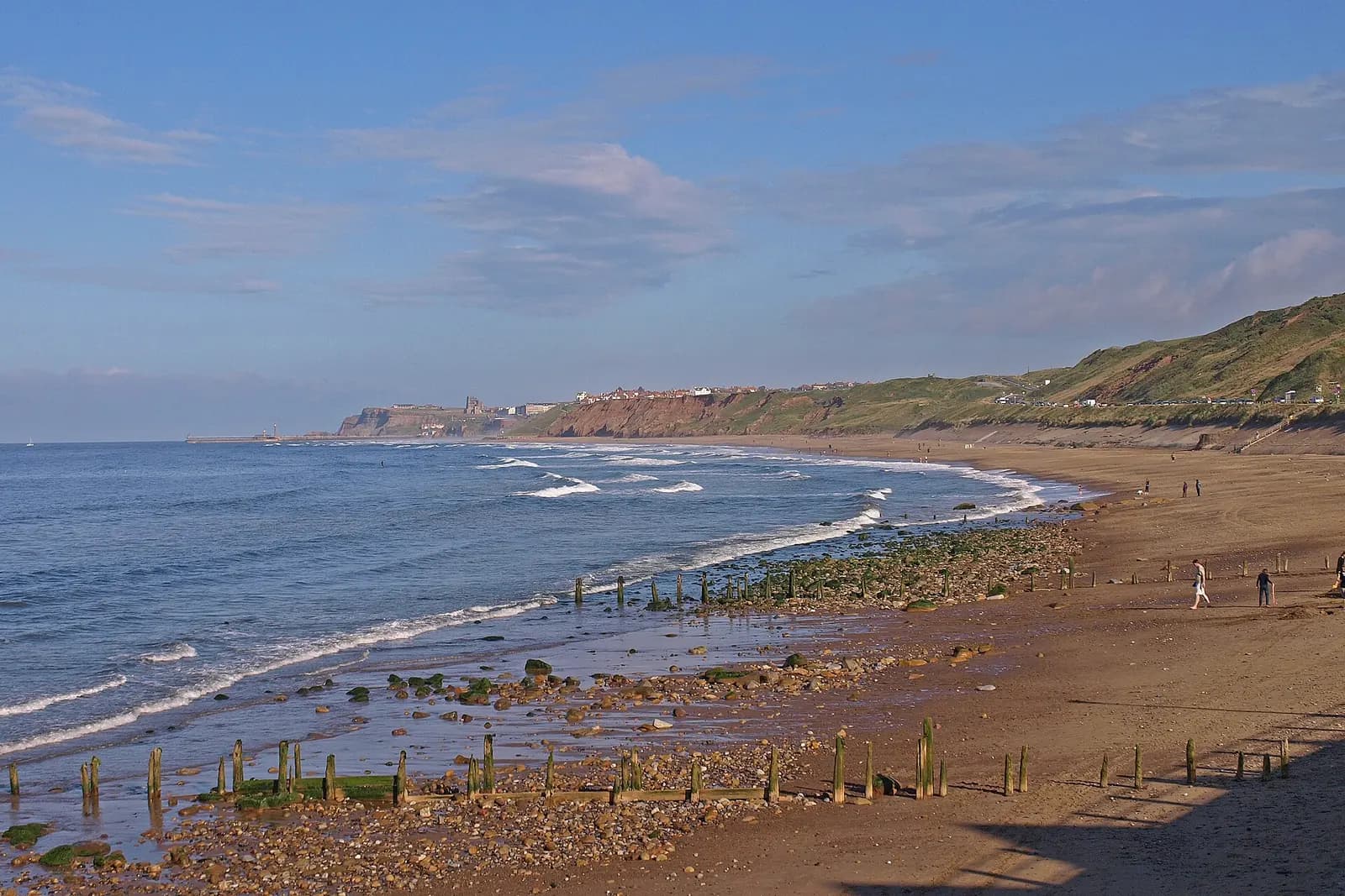 Waves on the long sandy beach at Sandsend, with the coast curving back towards Whitby