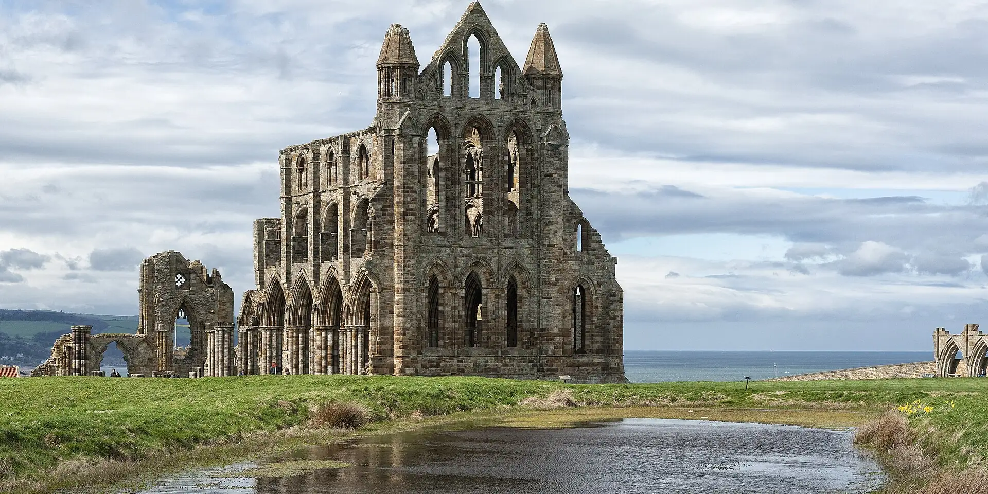 The gaunt ruined arches of Whitby Abbey on the clifftop under a cloudy sky