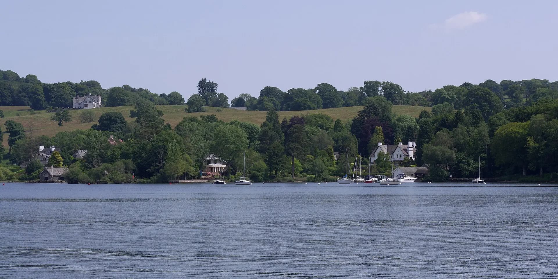 Lake Windermere's calm water, with sailing boats and wooded hills along the far shore