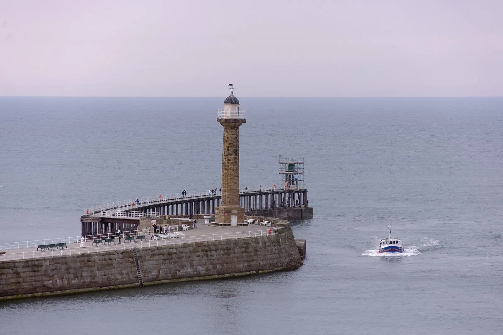 Whitby's west pier and lighthouse at the harbour entrance, with a boat heading out to sea