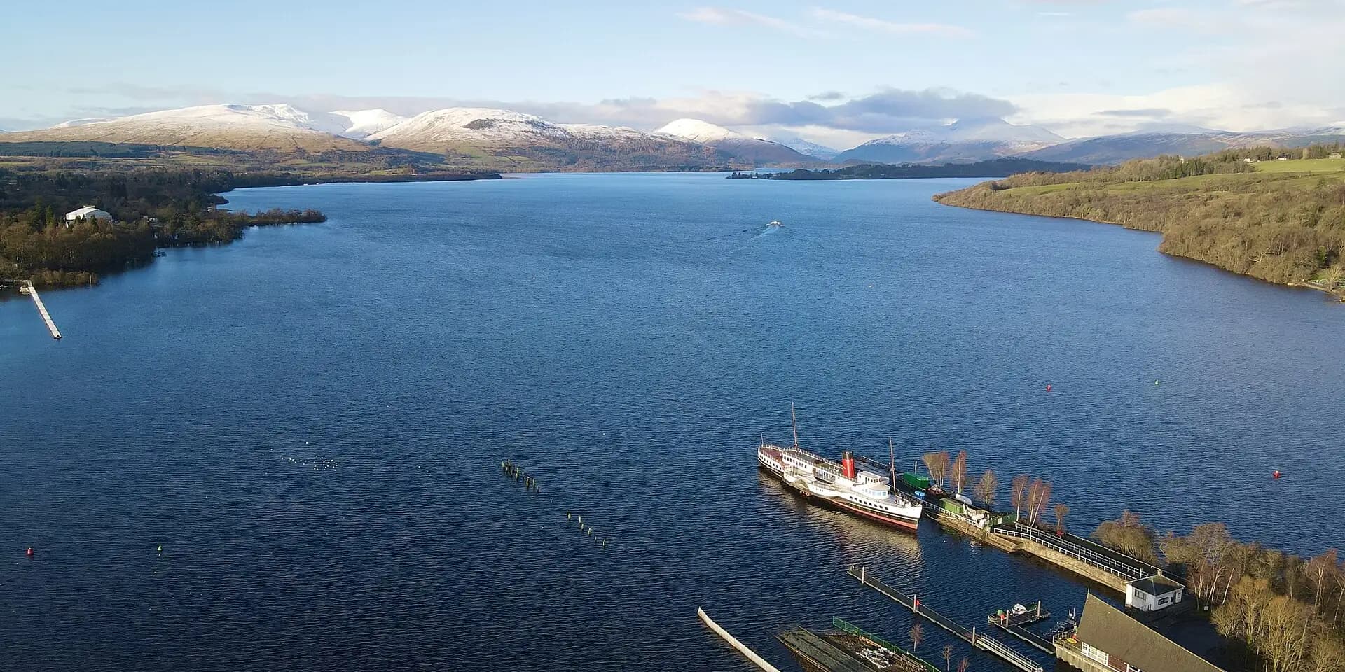Loch Lomond stretching away to snowy mountains, with the paddle steamer Maid of the Loch at Balloch pier