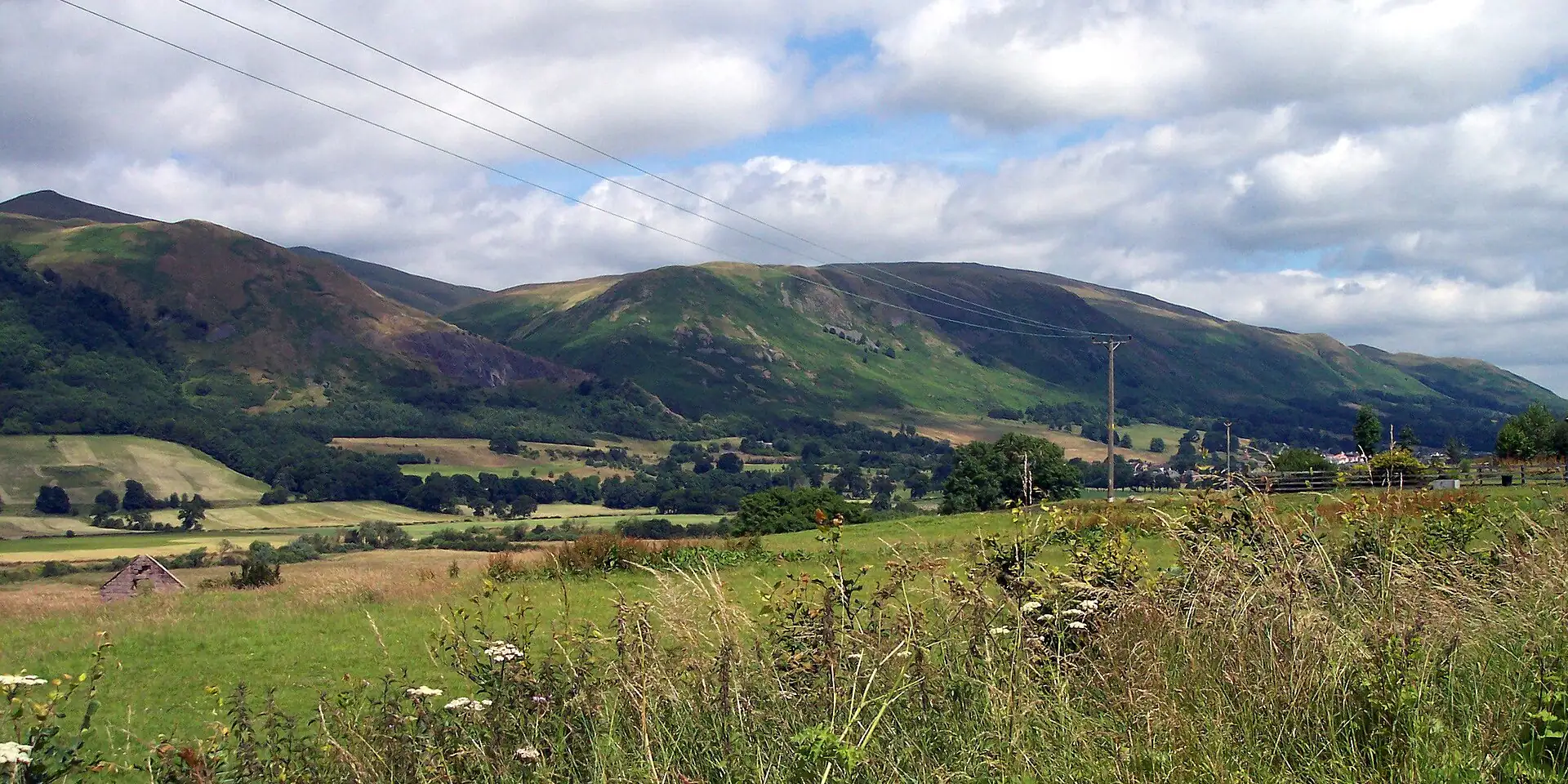 Green slopes of the Ochil Hills above farmland and meadow grass