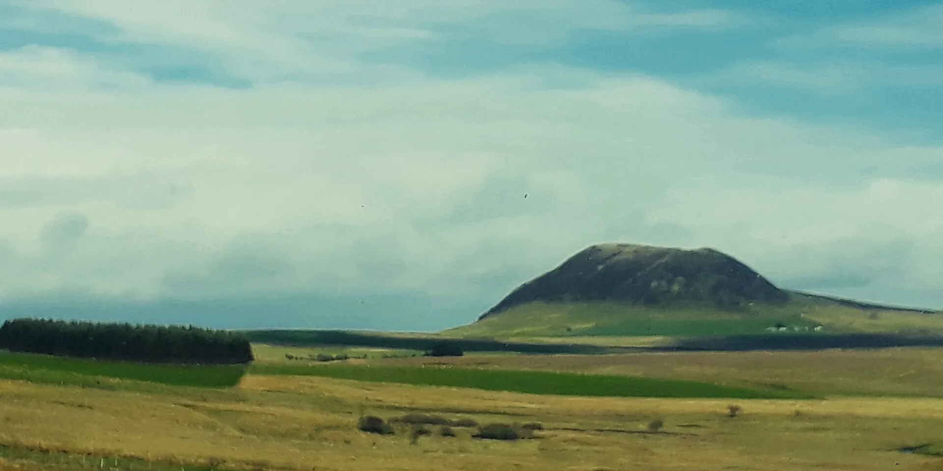 The rounded green hump of Slemish mountain rising above open farmland