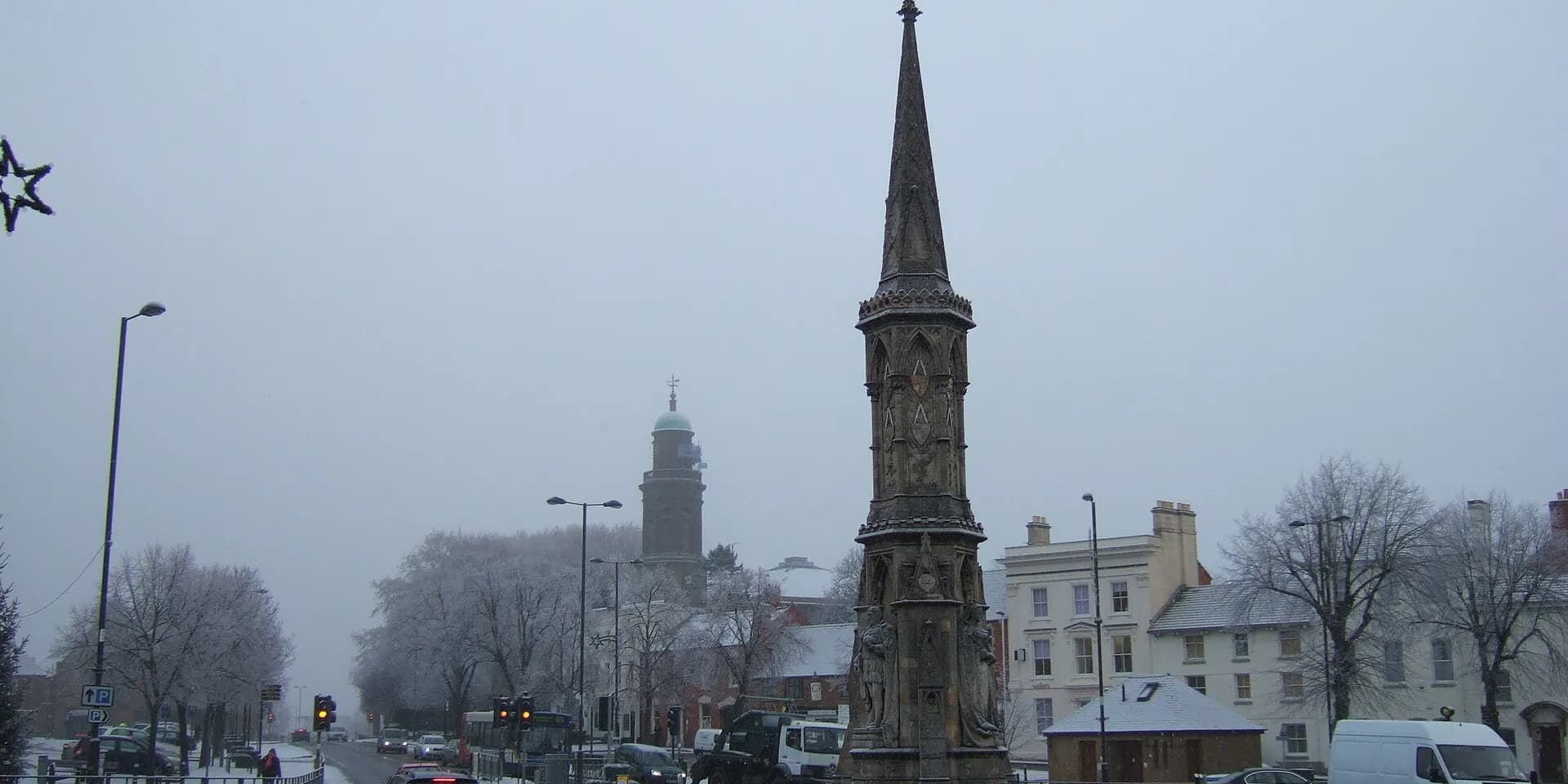 The tall stone spire of Banbury Cross on a misty winter day, with the Horsefair beyond