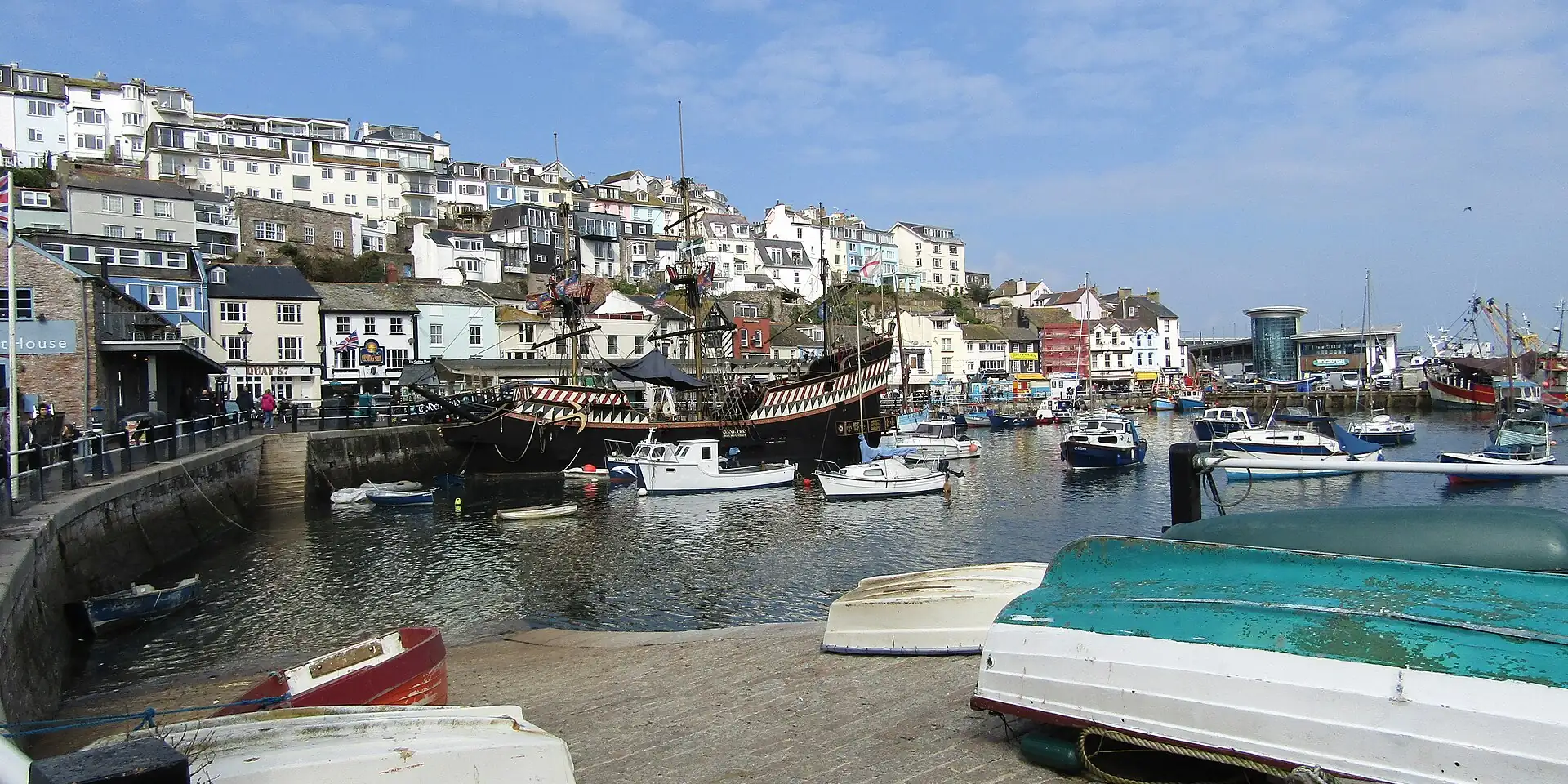 Brixham's inner harbour with small boats and the replica of the Golden Hind, below colourful houses on the hill