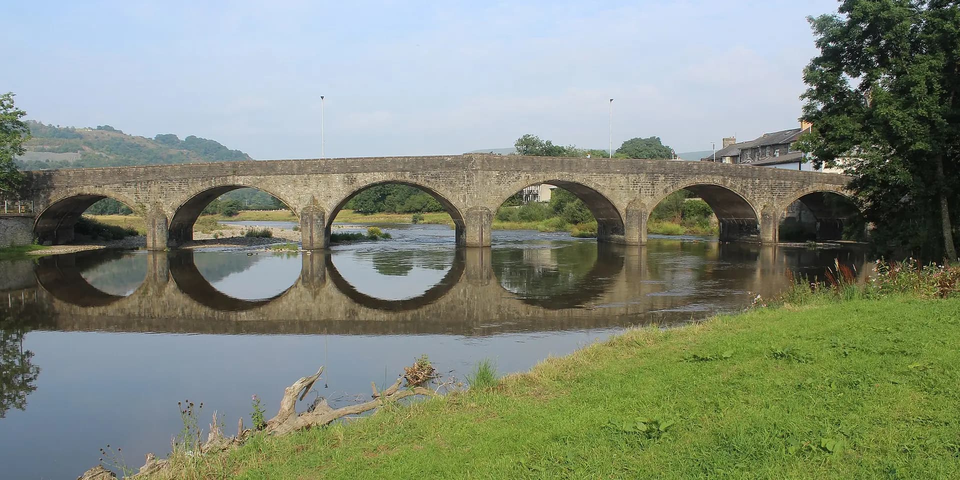 The stone arches of the bridge over the River Wye at Builth Wells, reflected in the water