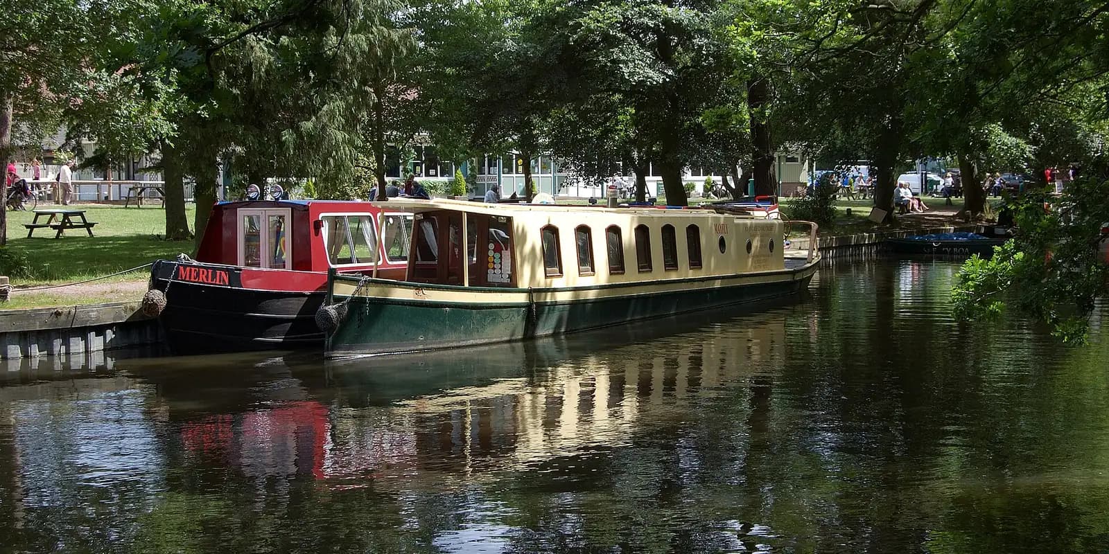 A traditional canal boat moored on the tree-lined Basingstoke Canal at Mytchett