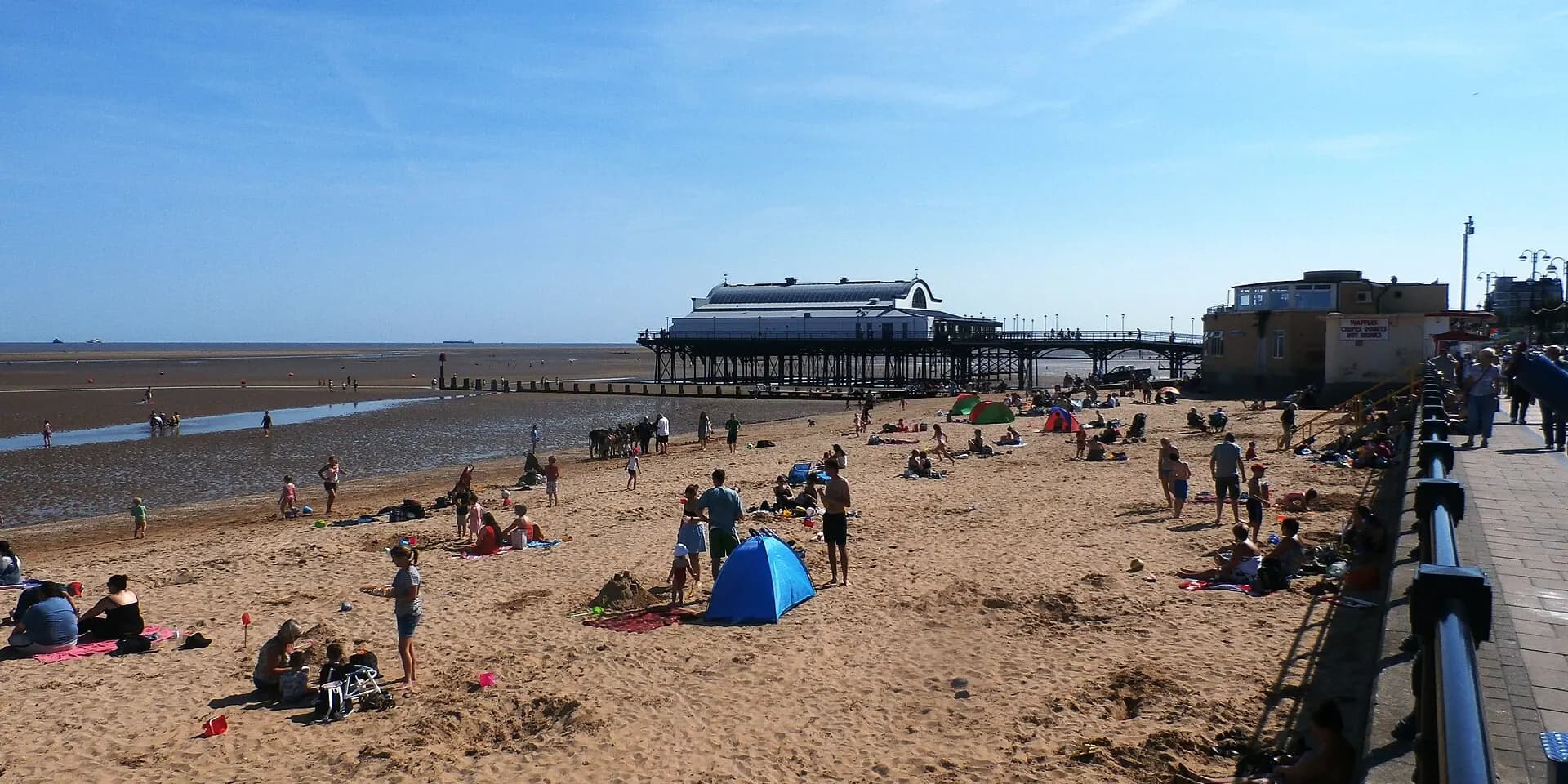 Cleethorpes beach on a sunny day, with families on the sand and the pier stretching out to sea