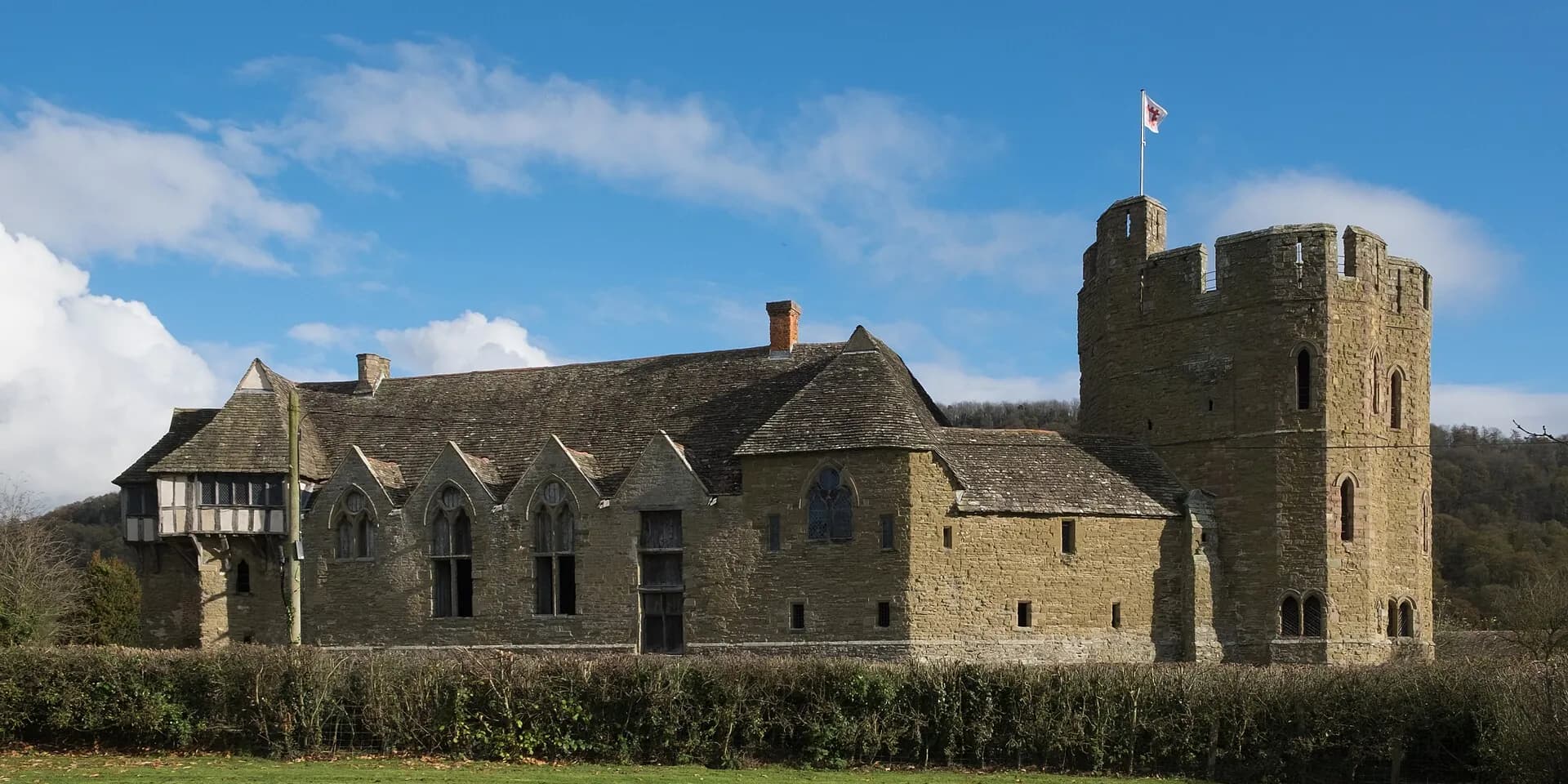 Stokesay Castle, a medieval manor house with a stone tower and timbered gable, under a blue sky