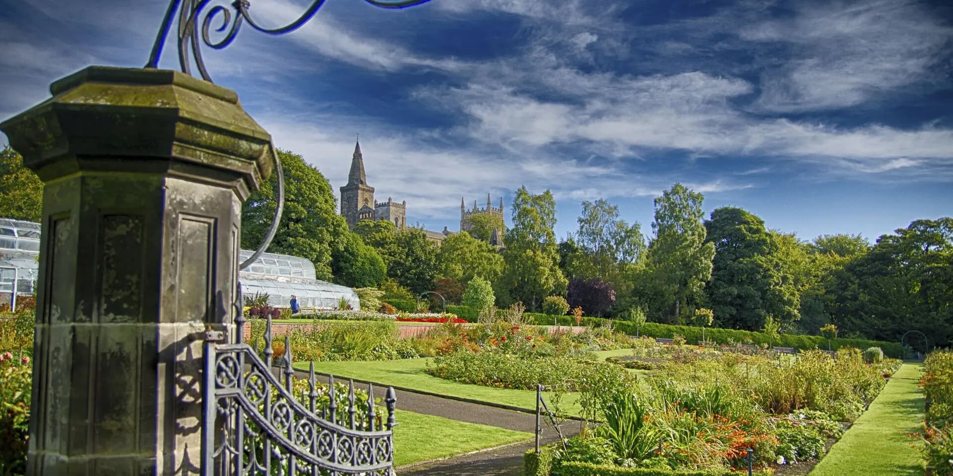 Flower borders and lawns in Pittencrieff Park, with the towers of Dunfermline Abbey above the trees