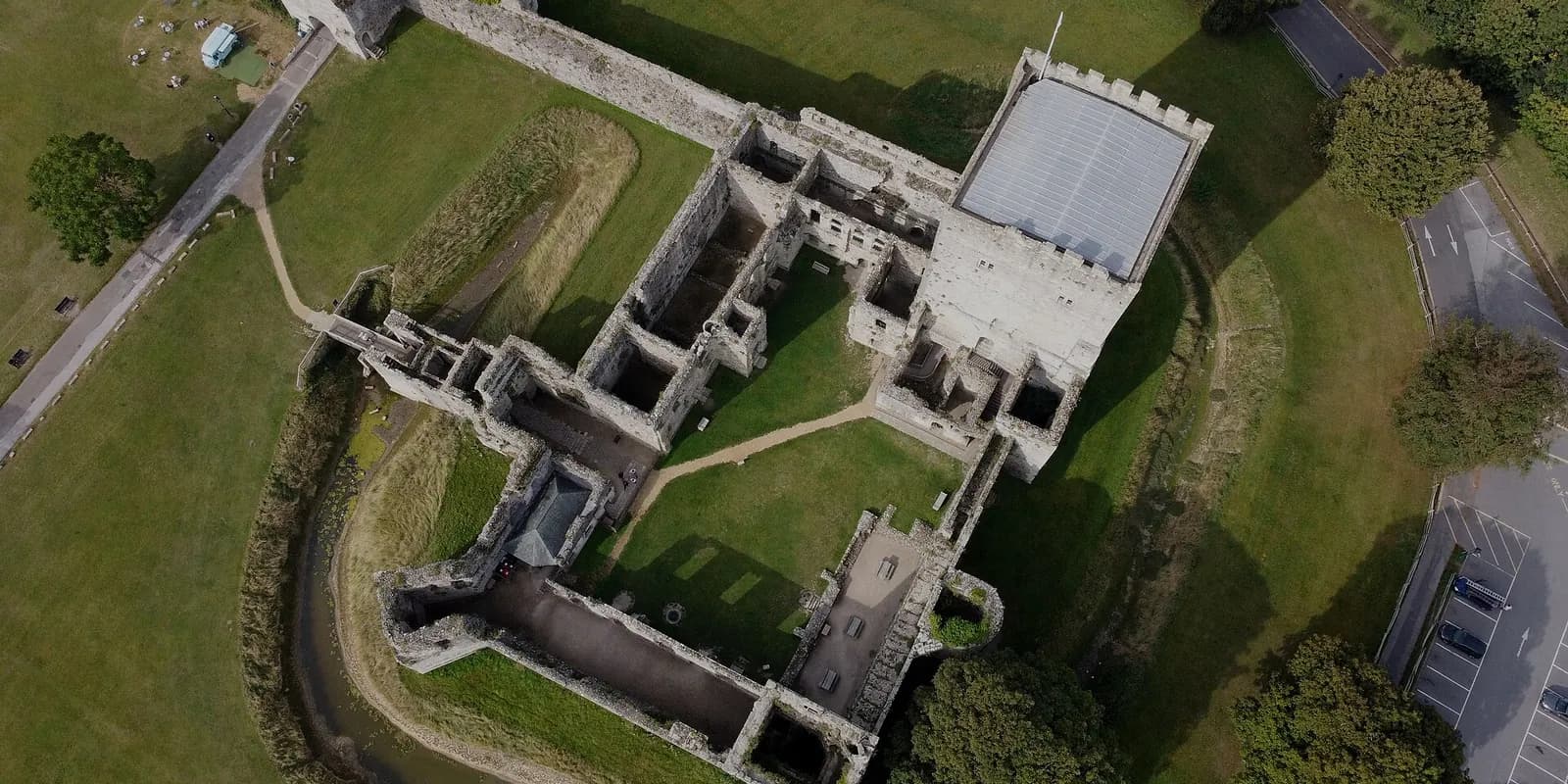 Portchester Castle seen from above: its square keep and Roman walls set in green grass