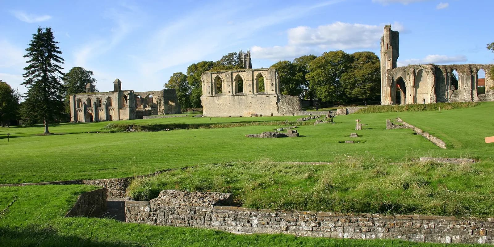 The ruined stone walls of Glastonbury Abbey on wide green lawns