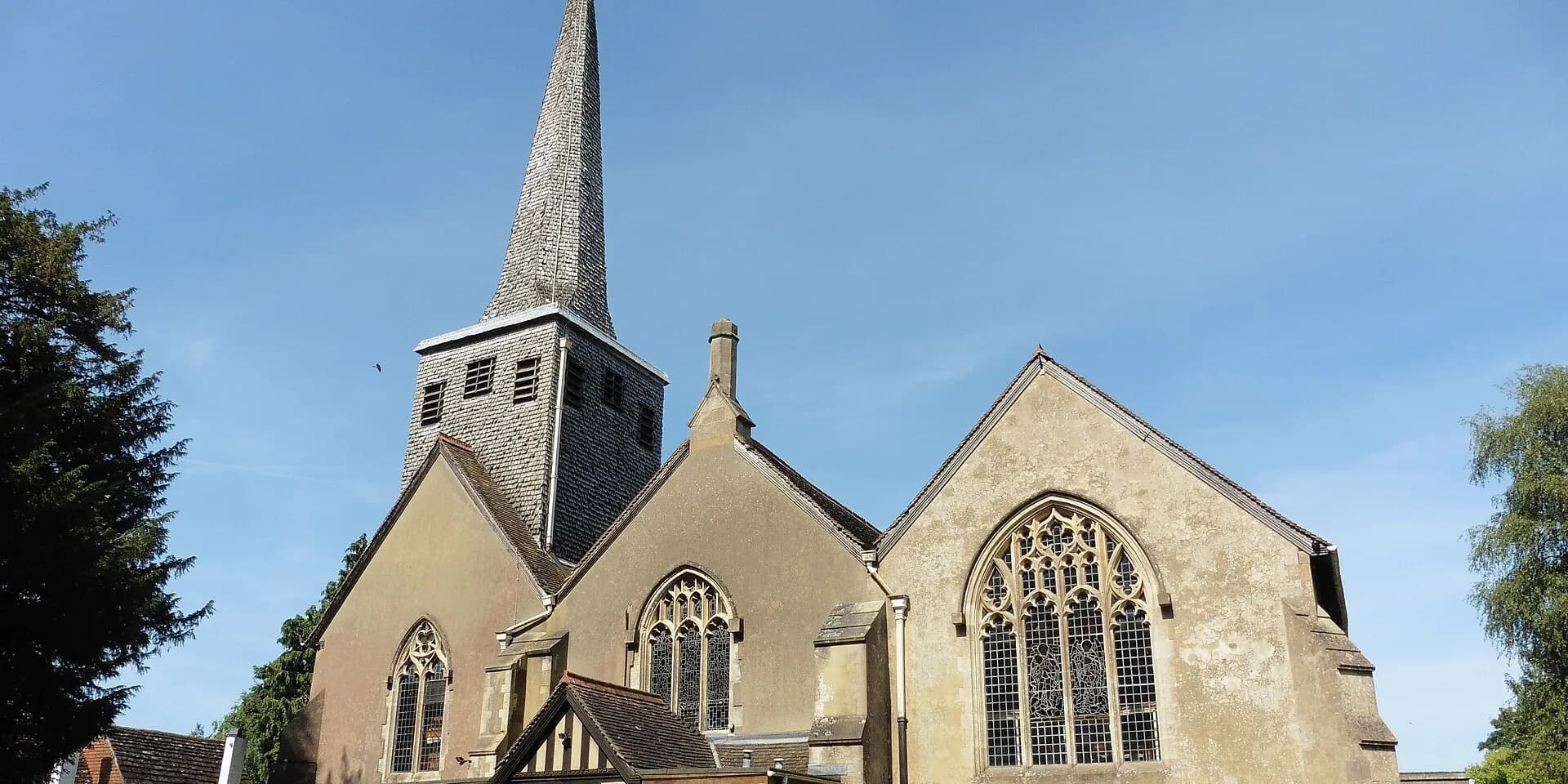 St Bartholomew's Church in Horley, with its shingled spire against a blue sky
