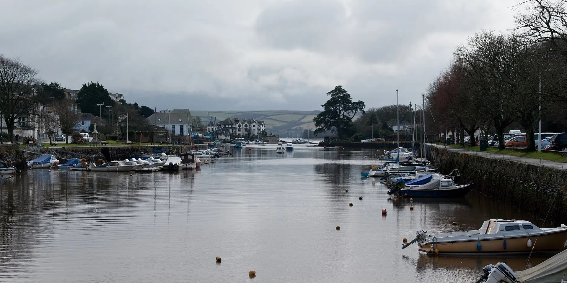 Small boats moored along Kingsbridge creek at the head of the estuary, on a grey winter's day