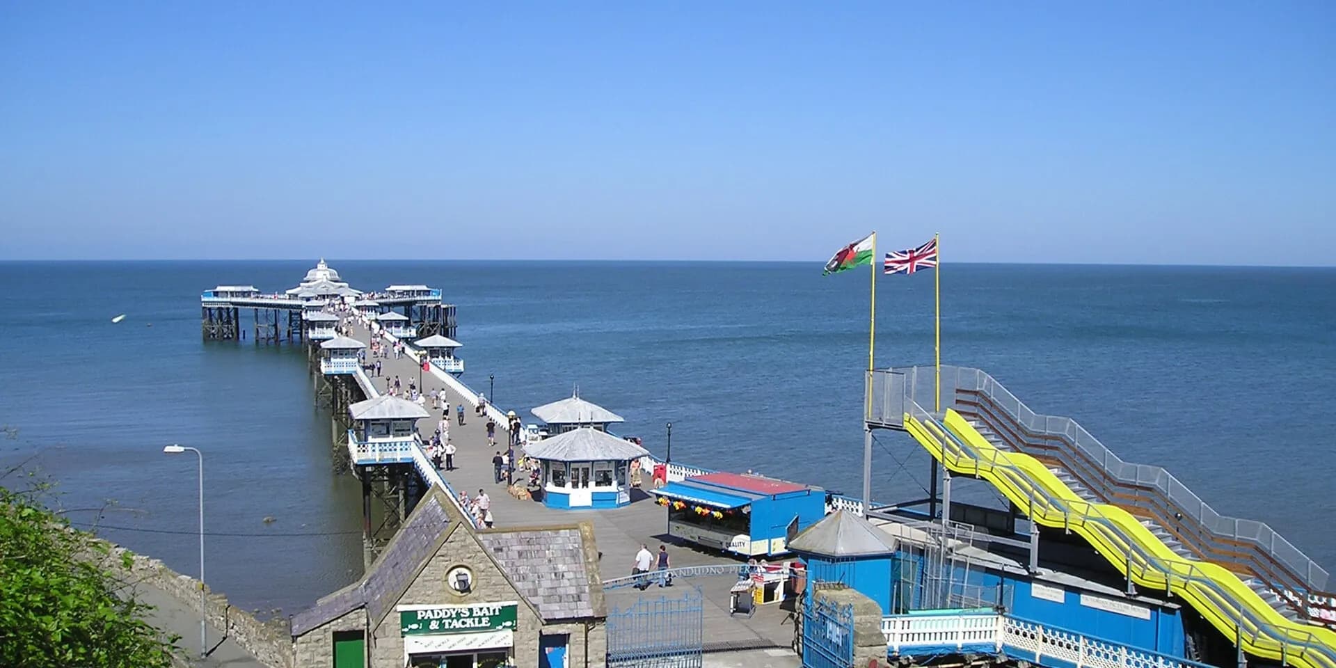 Llandudno Pier stretching out into a blue sea, seen from above on a sunny day