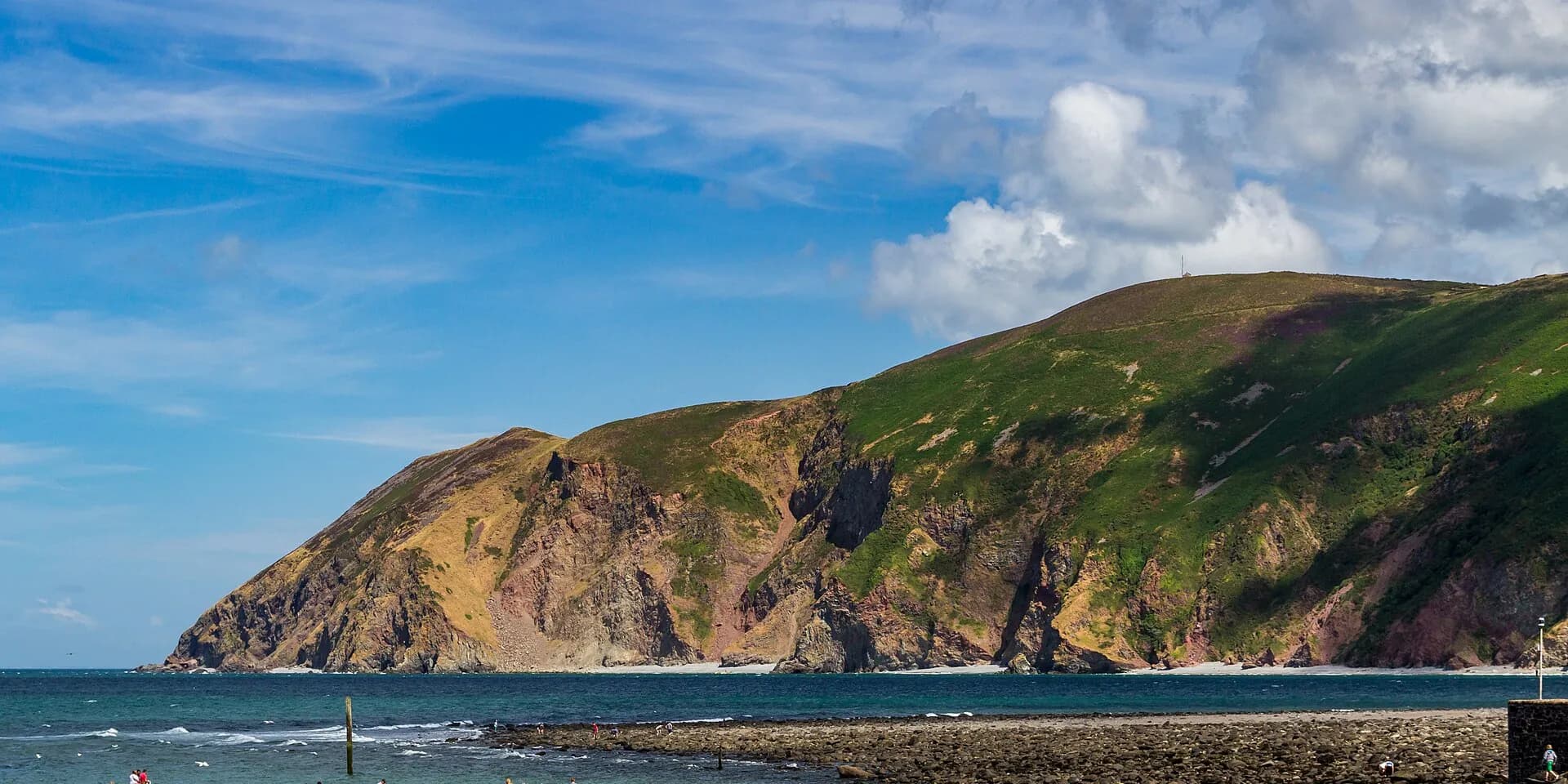 Green and rust-coloured cliffs rising above the sea on the coast at Lynmouth
