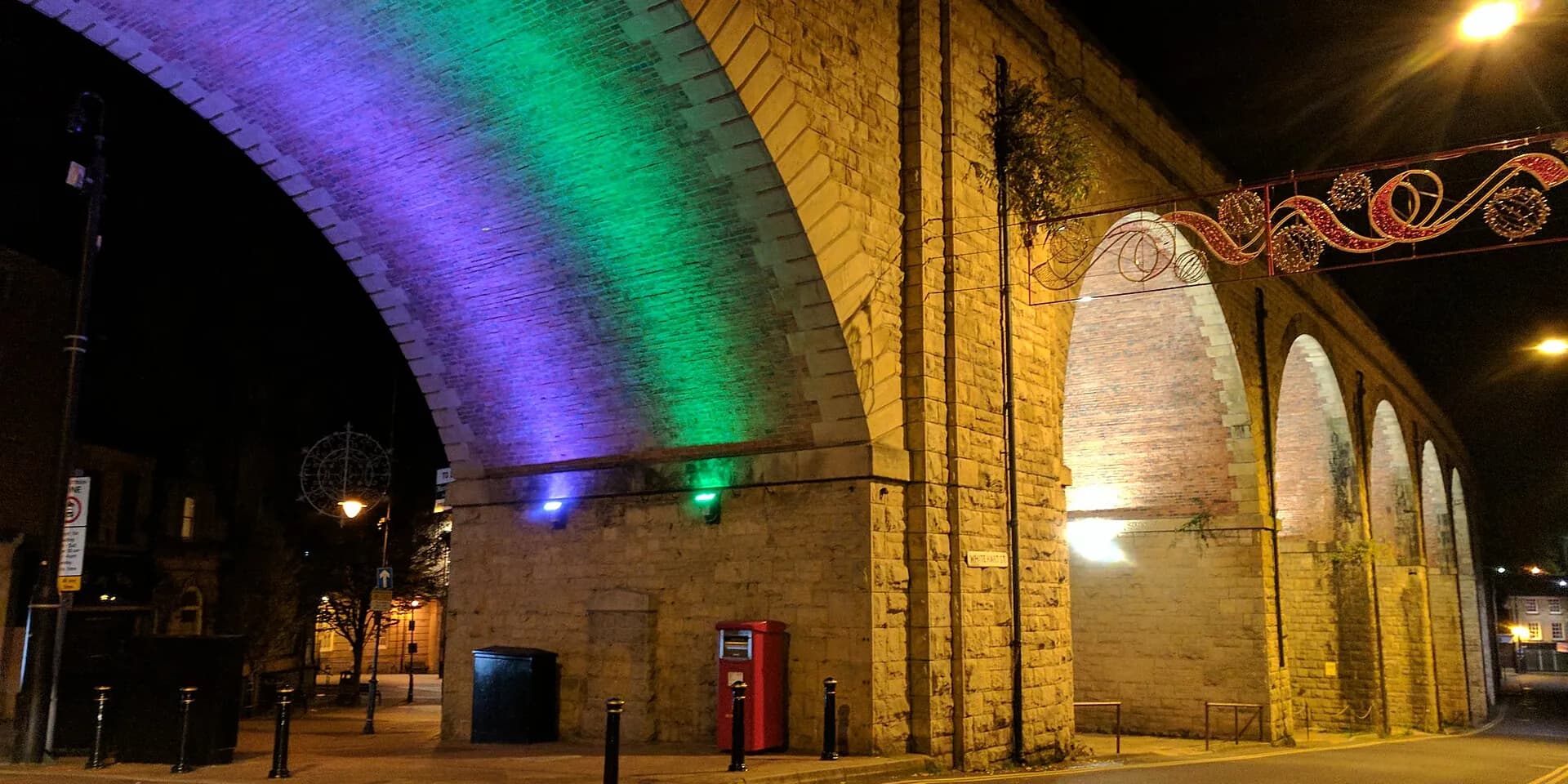 The stone arches of Mansfield's railway viaduct lit in rainbow colours at night