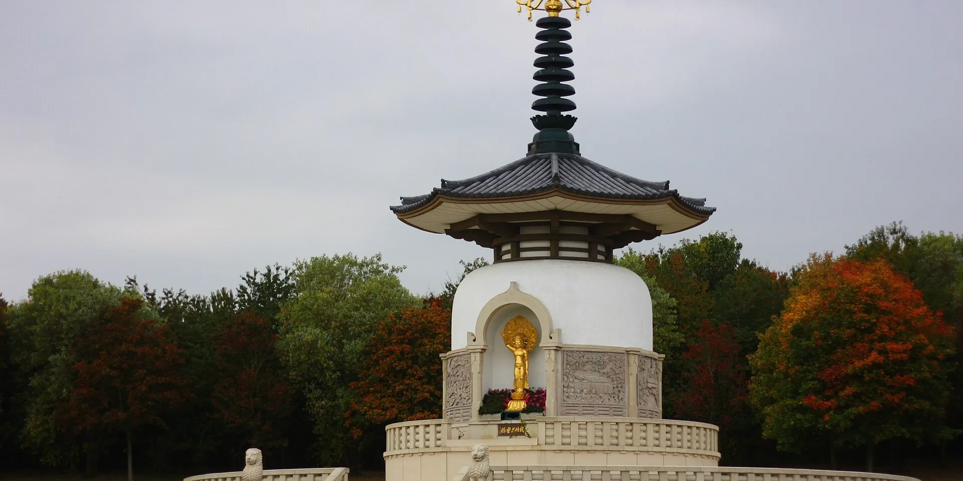 The white Peace Pagoda by Willen Lake, framed by autumn trees