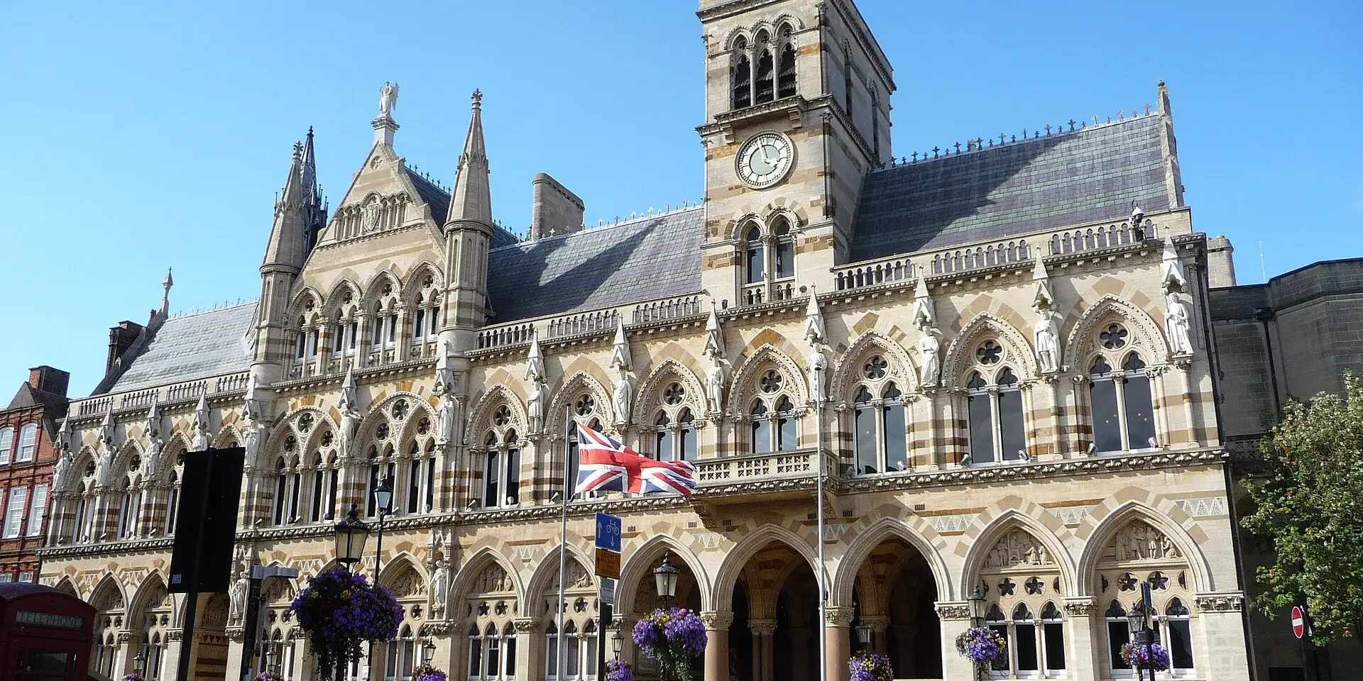 Northampton Guildhall's ornate Gothic stone front and clock tower, decorated with hanging flowers