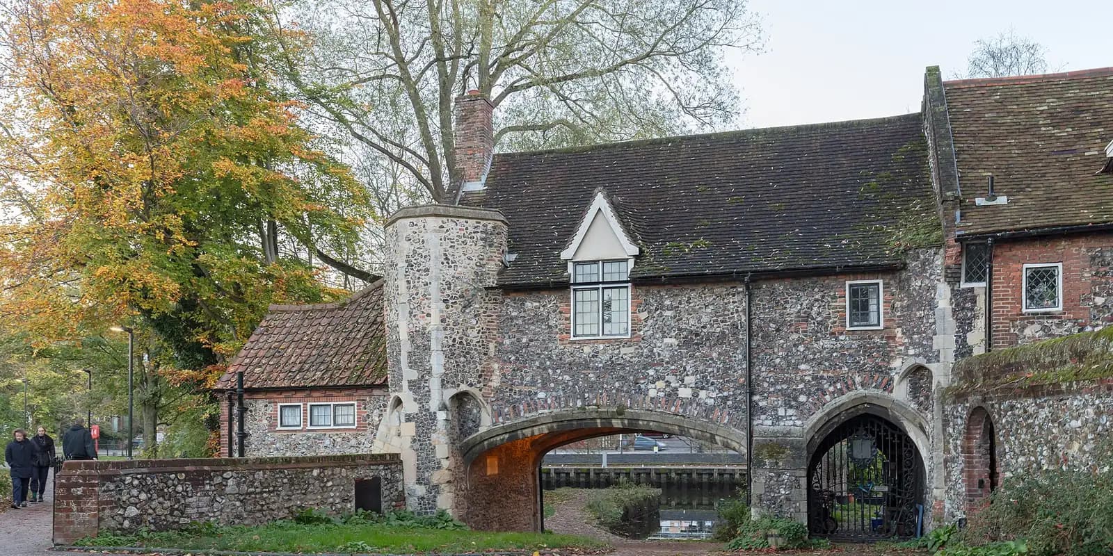 Pull's Ferry, a medieval flint watergate on the river in Norwich, among autumn trees
