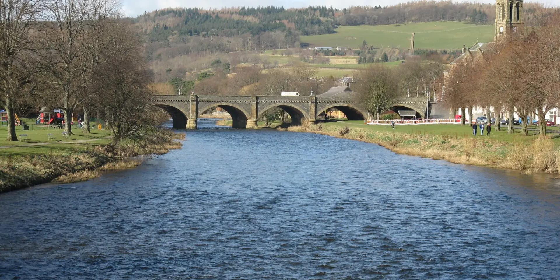 The River Tweed flowing through Peebles, with the old stone bridge and the town's church beyond