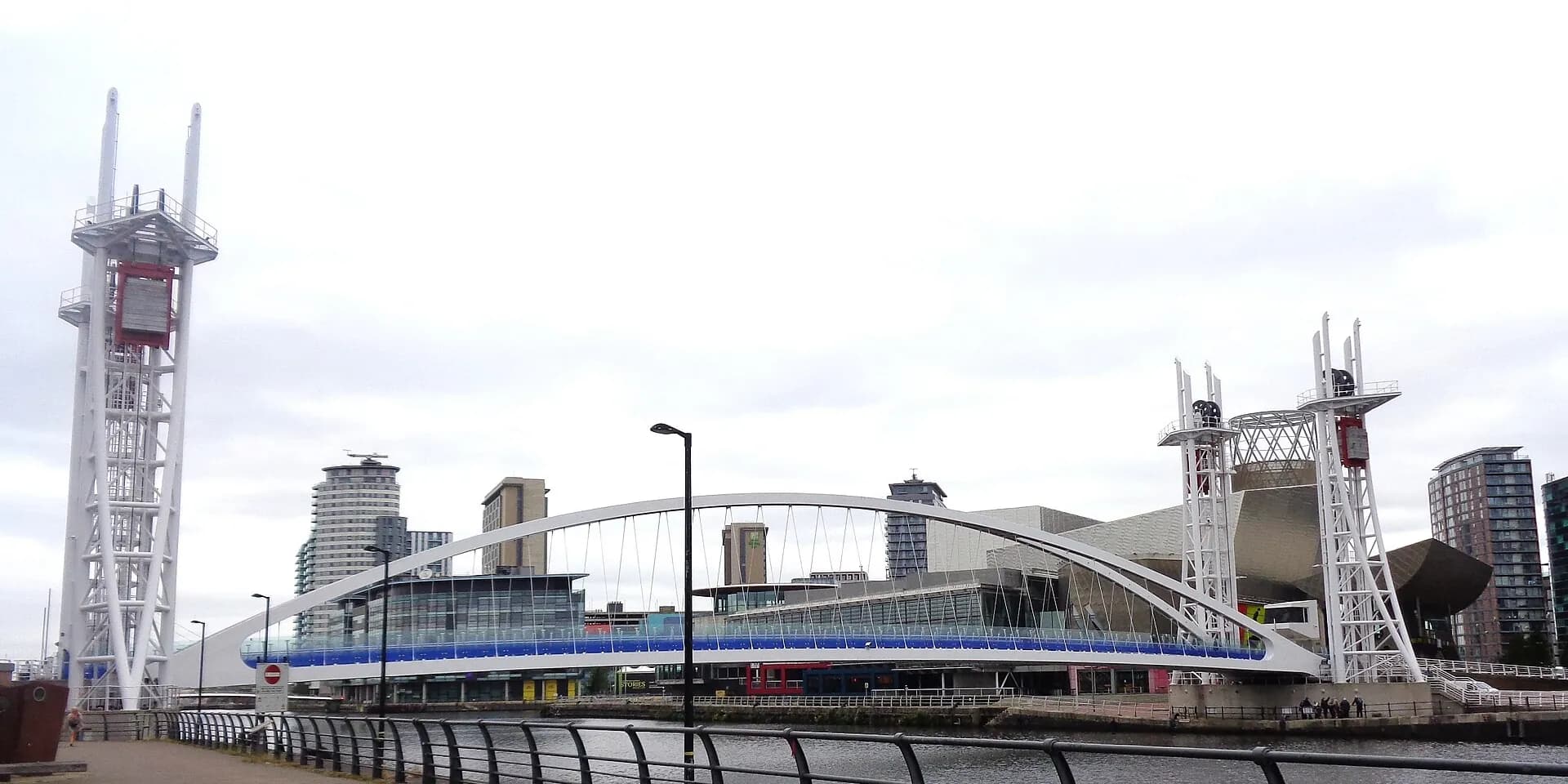 The white lift bridge across the water at Salford Quays, with modern buildings and towers beyond