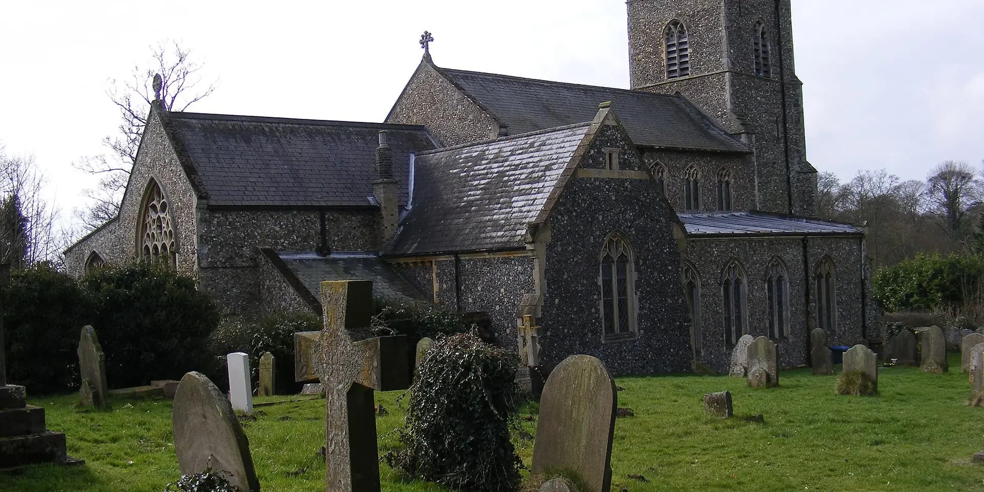 The flint tower and nave of St John the Baptist Church in Saxmundham, behind its churchyard