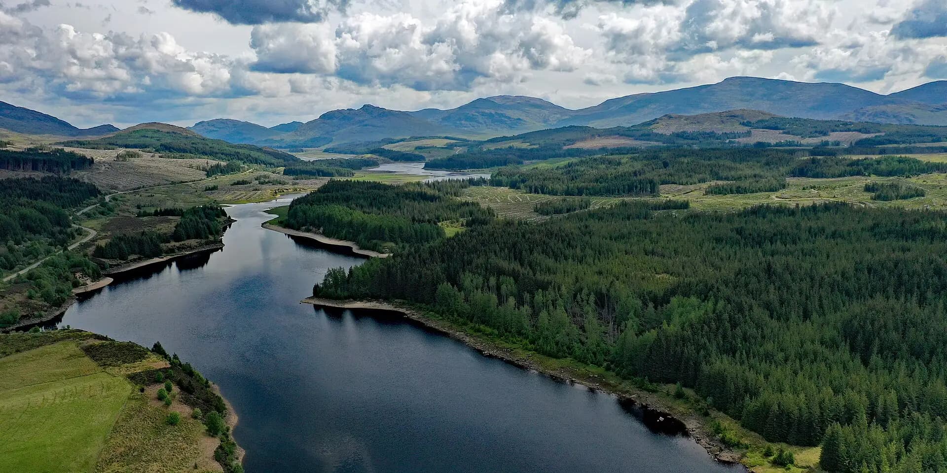 The River Spean winding through forest and moorland below a ring of mountains, seen from the air