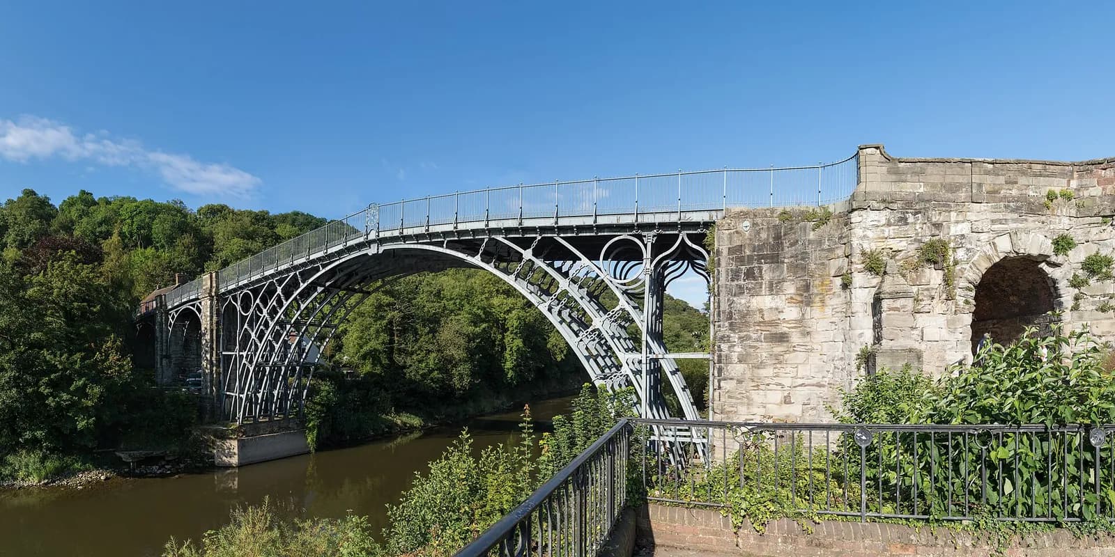 The Iron Bridge's cast-iron arch over the River Severn among green trees