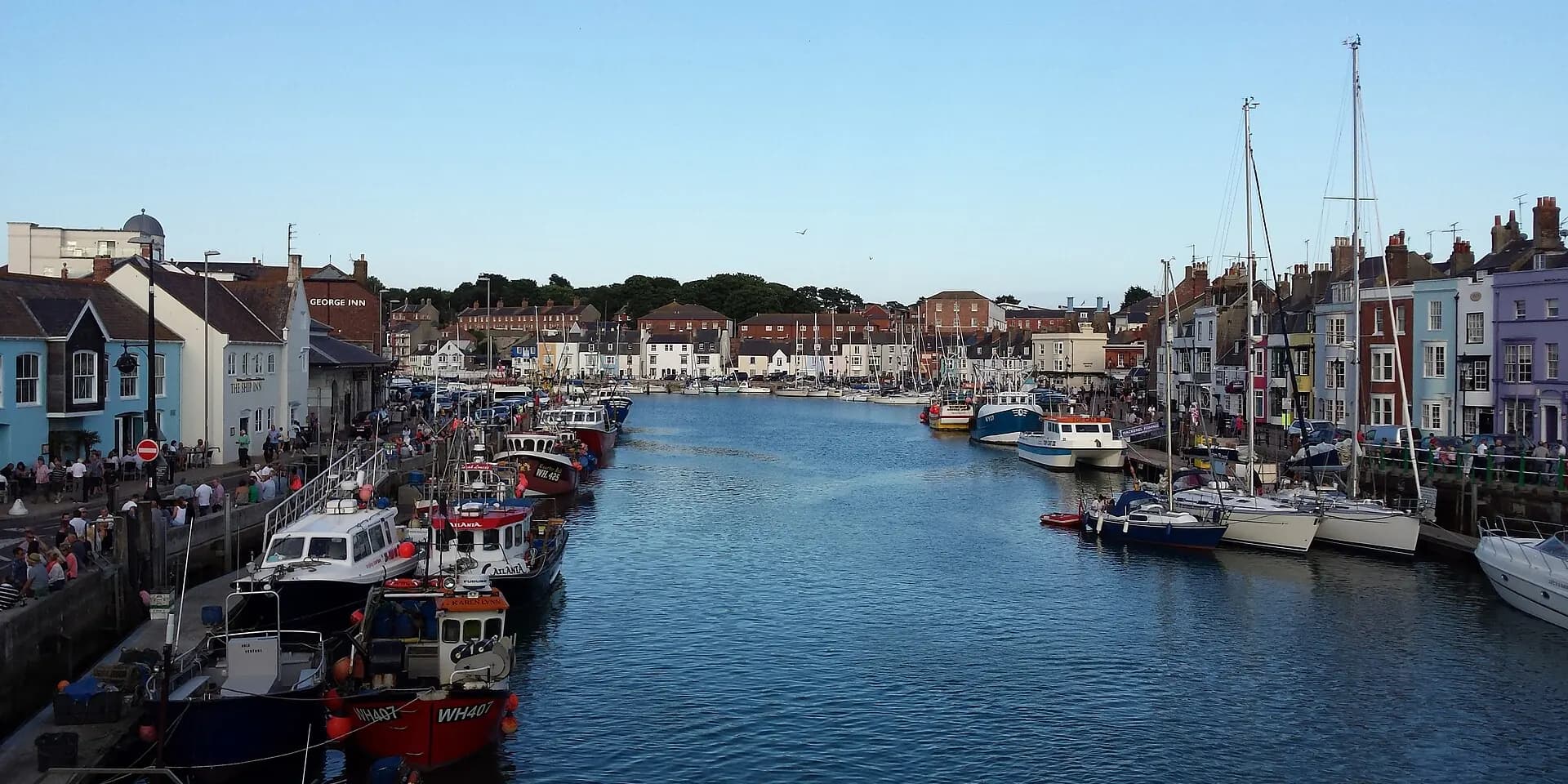 Weymouth harbour lined with colourful houses and moored boats