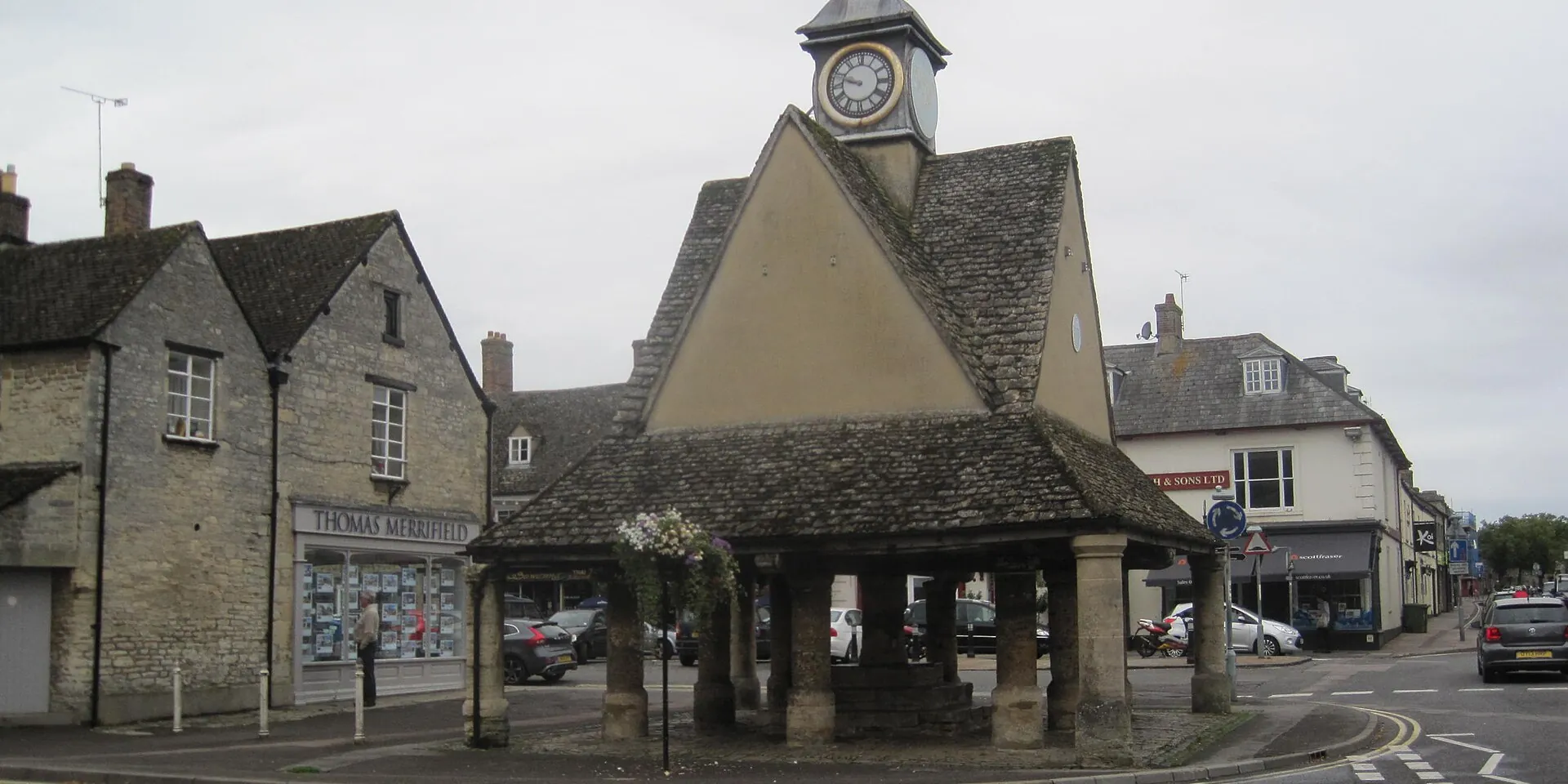 Witney's Buttercross, an old stone market shelter with a clock turret, among Cotswold stone buildings